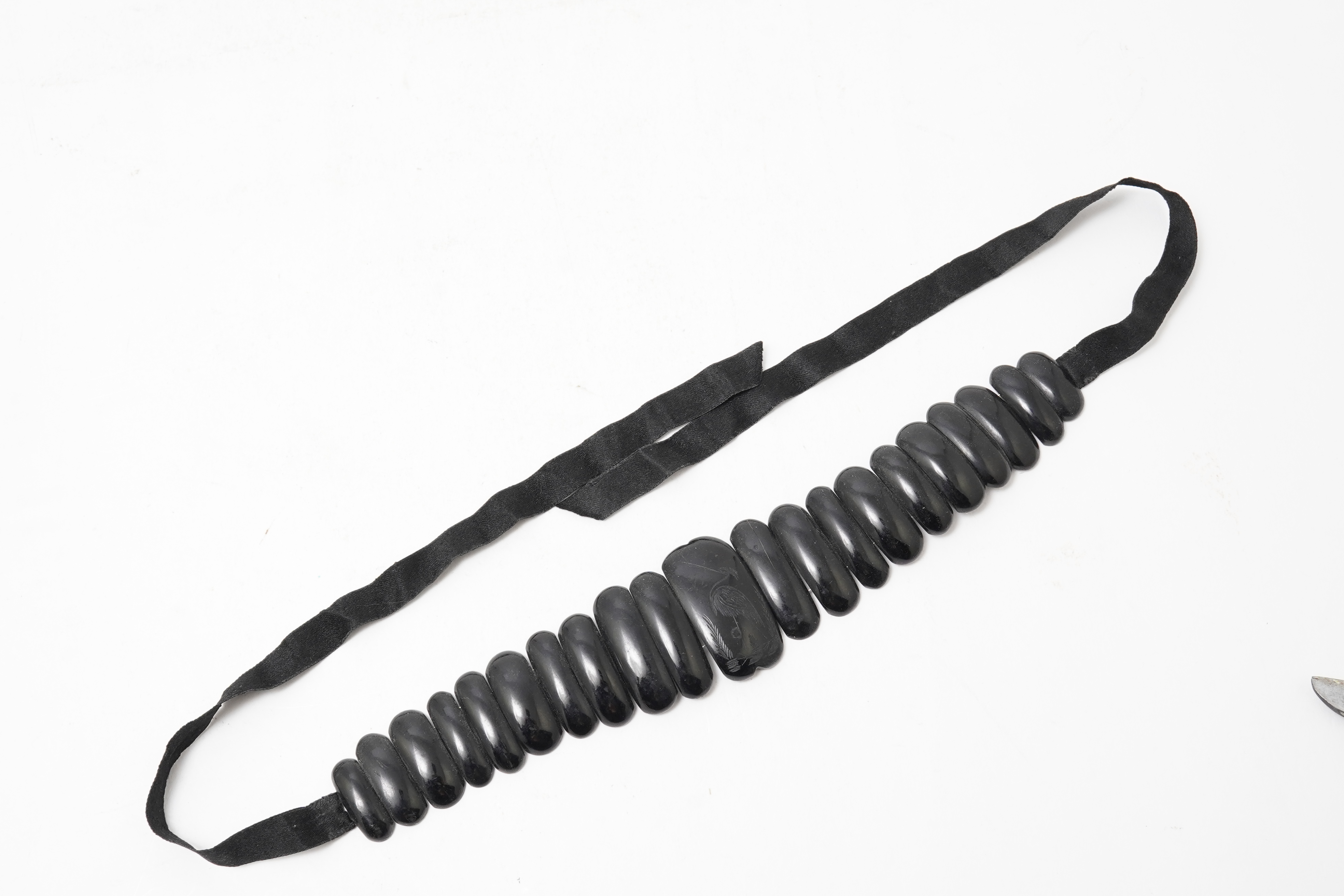 A collection of jewels, comprising: a moulded bog oak brooch depicting a hand holding a posy, length 7.4cm; a carved jet brooch depicting a Gothic ruin, possibly part of Whitby Abbey; a necklace composed of polished pane